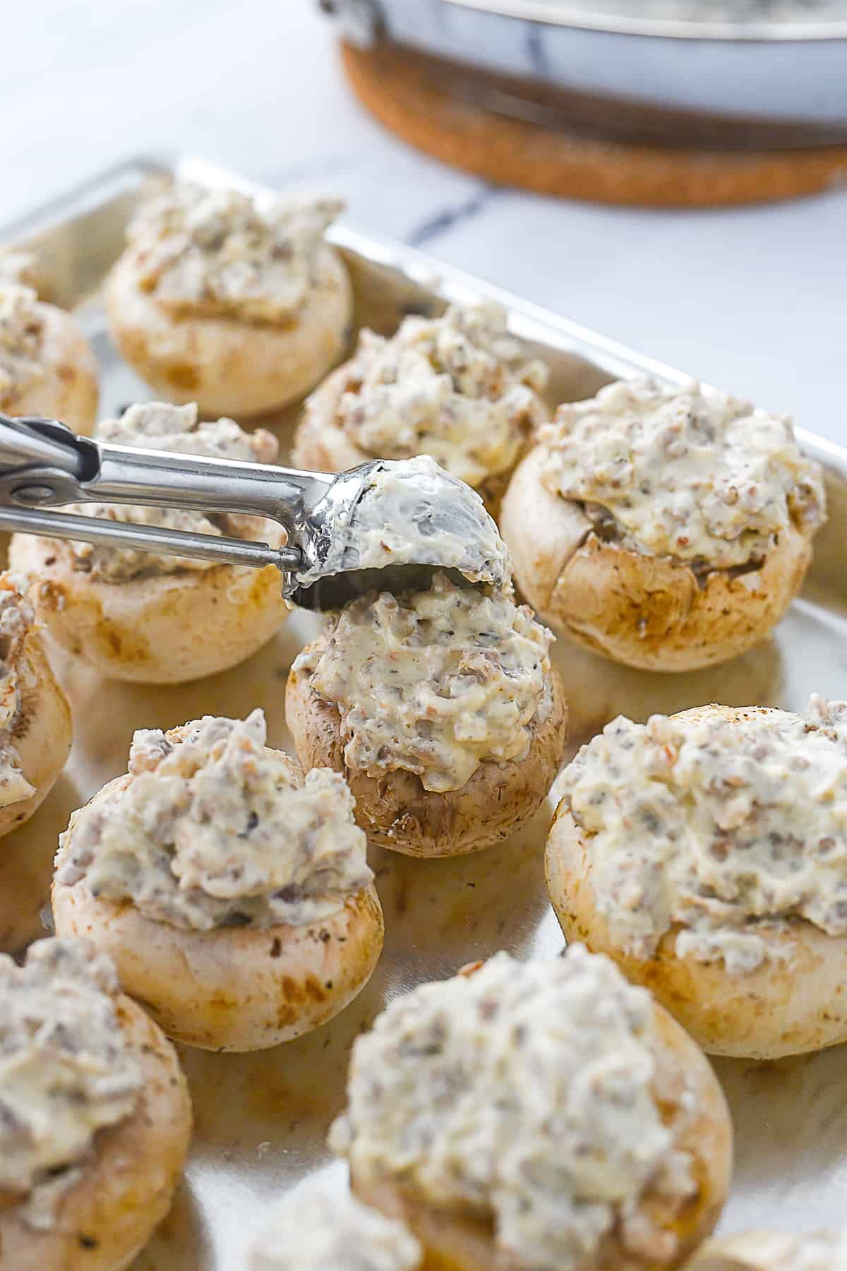 placing a scoop of sausage mixture into mushroom.