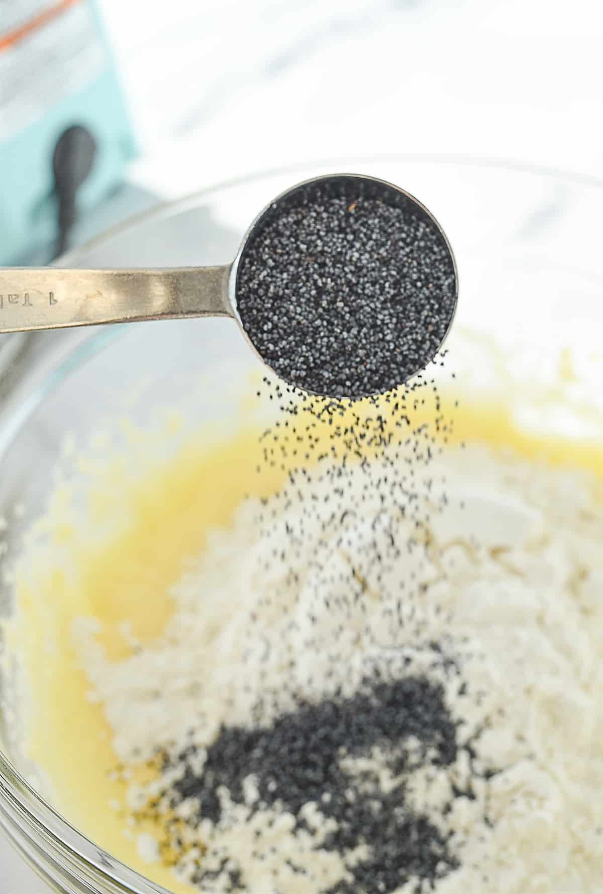 pouring poppyseeds into cake batter