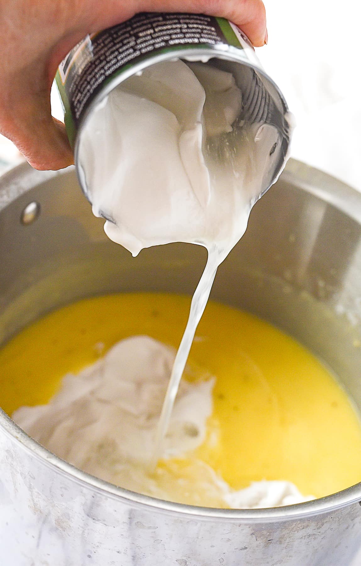 adding coconut milk to soup