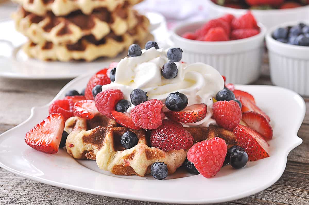 liege waffle with berries and whipped cream on top