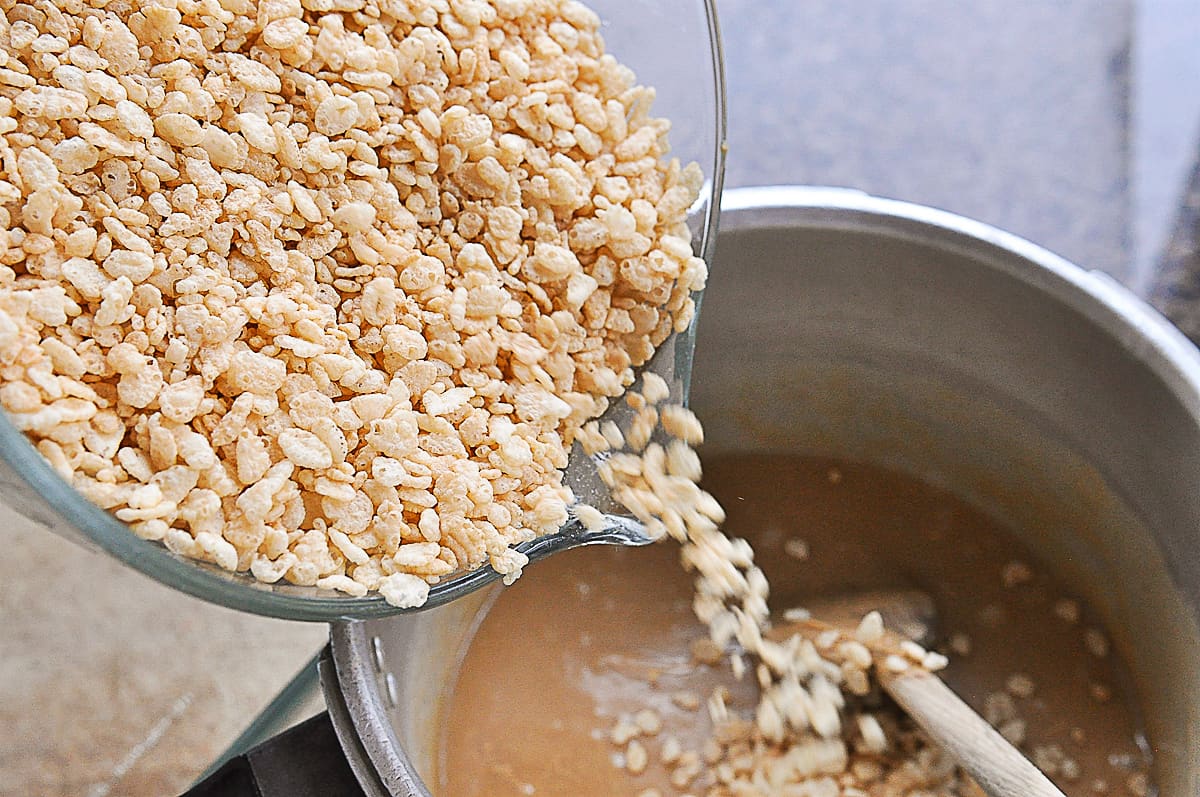 pouring crispy rice cereal into a pan