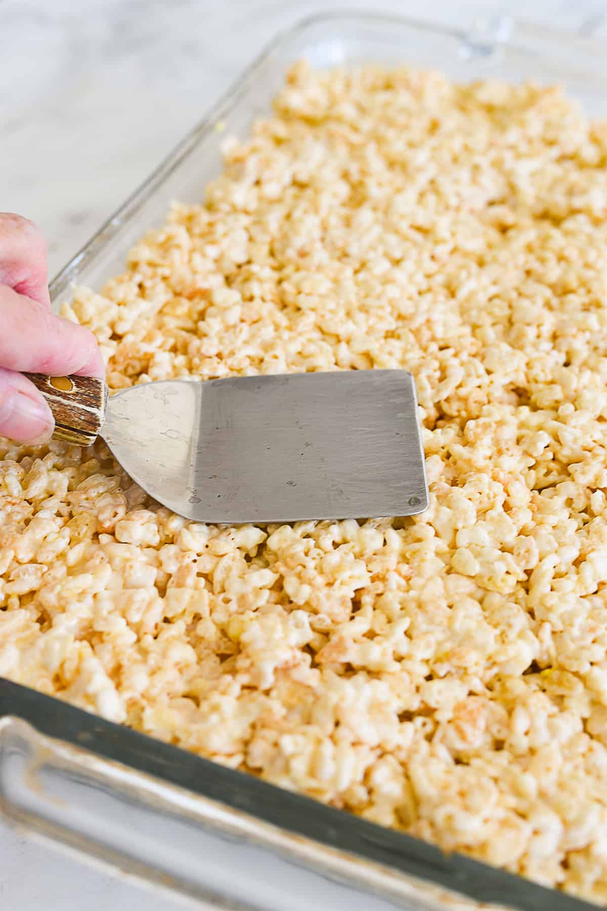 pressing down rice krispie treats into a pan