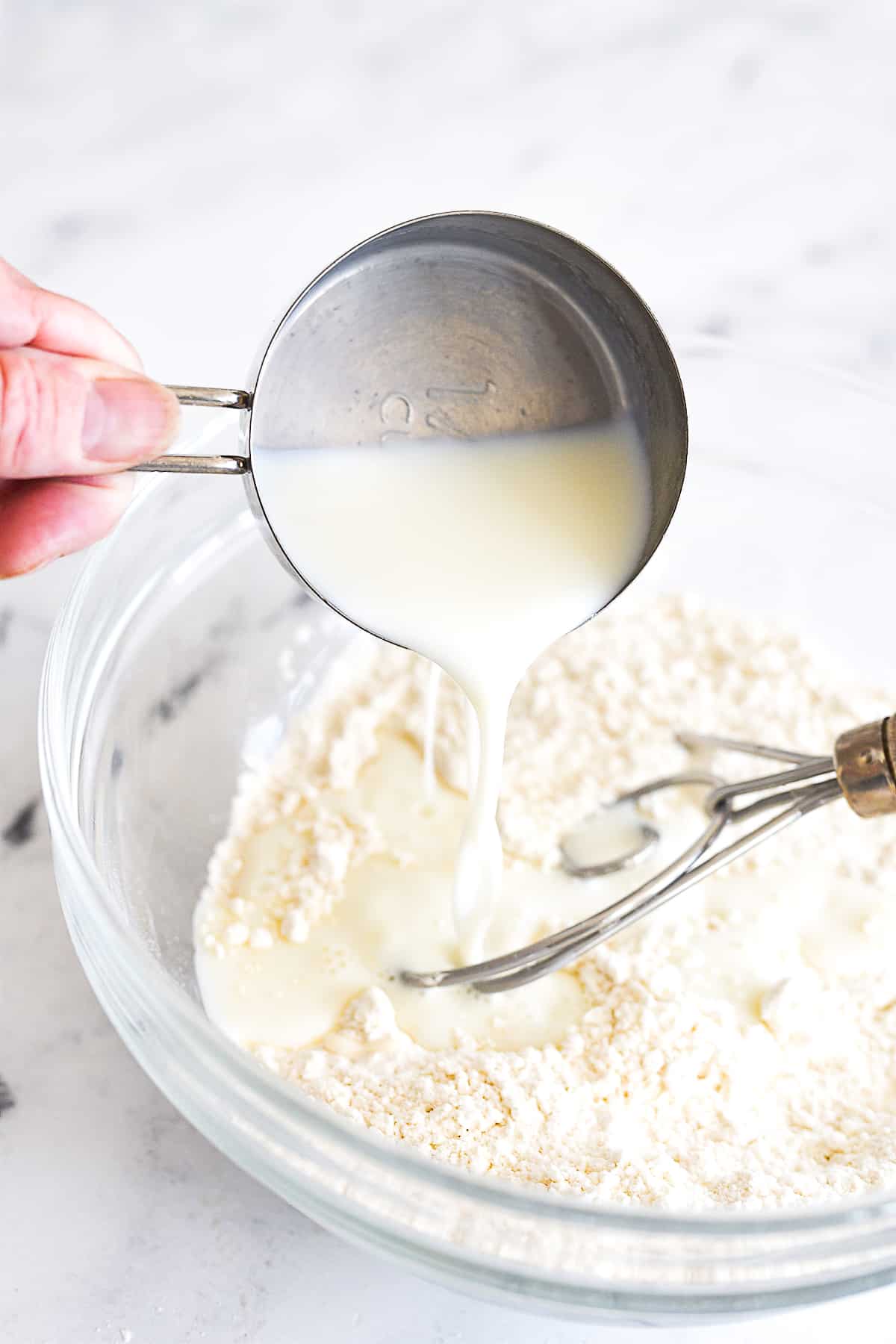 pouring milk into a bowl with flour