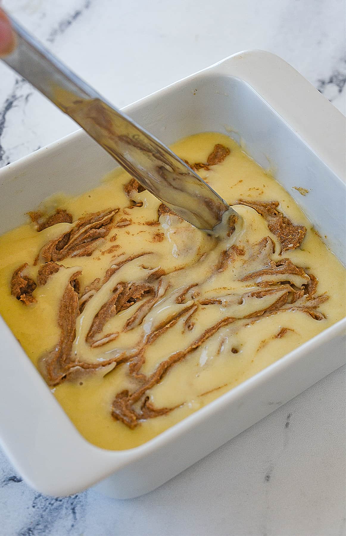 knife swirling batter in baking dish