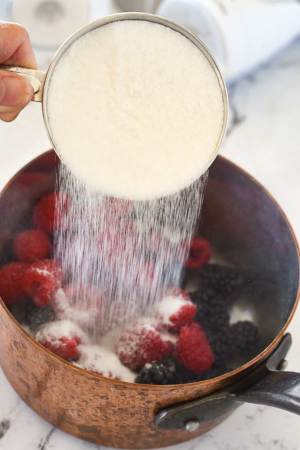 ADDING SUGAR TO BERRIES IN SAUCEPAN