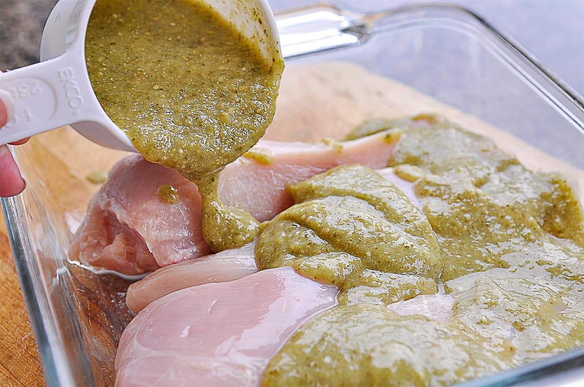 pouring salsa verde over chicken breasts