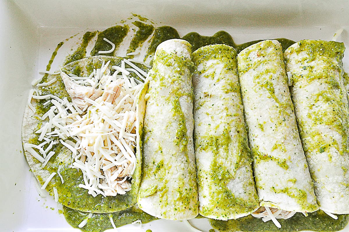 rolling up green chili enchiladas in a pan