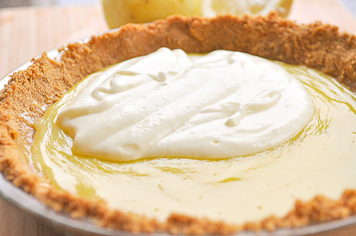 pouring whipped cream mixture over lemon chiffon pie