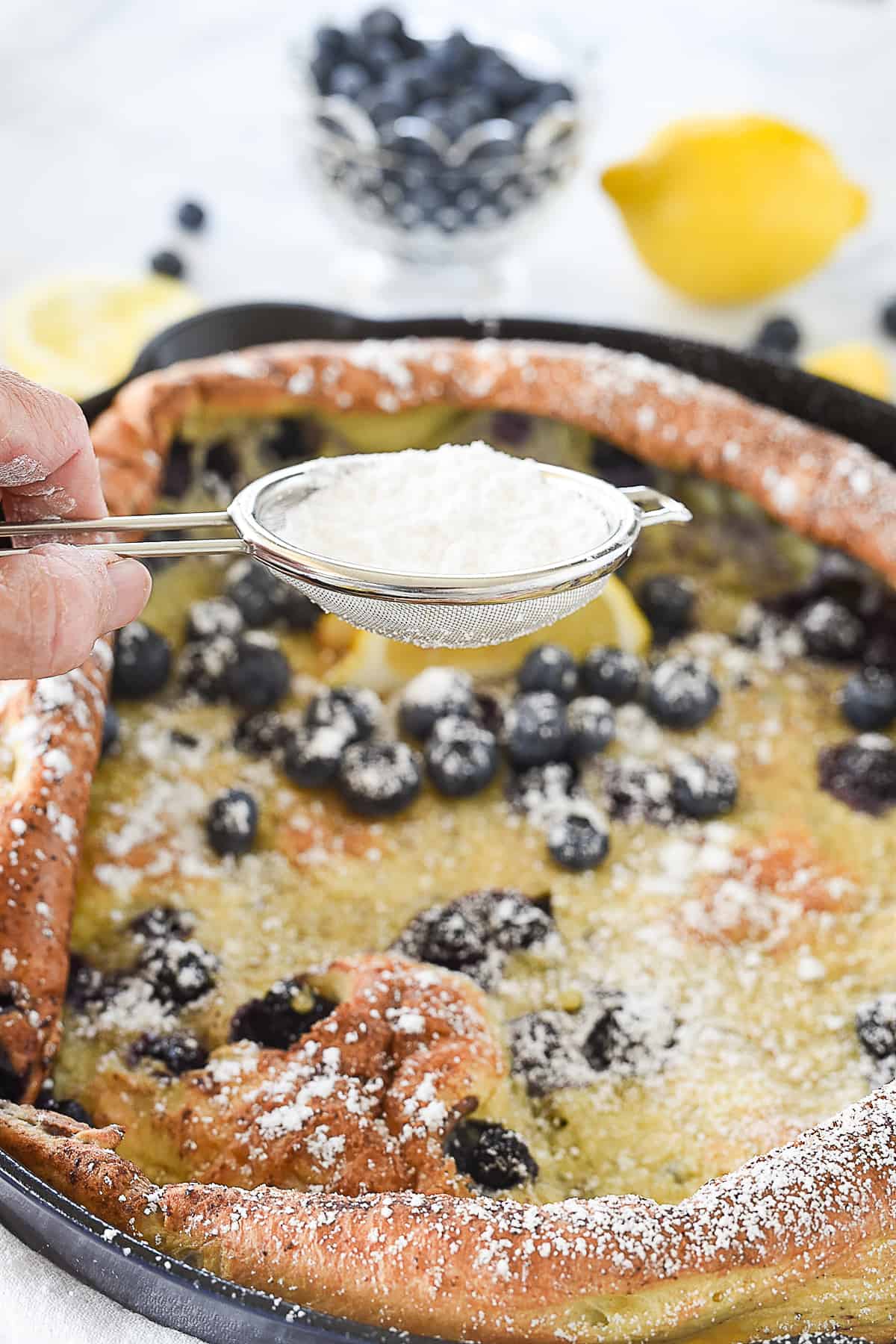 sprinkling powdered sugar on dutch baby