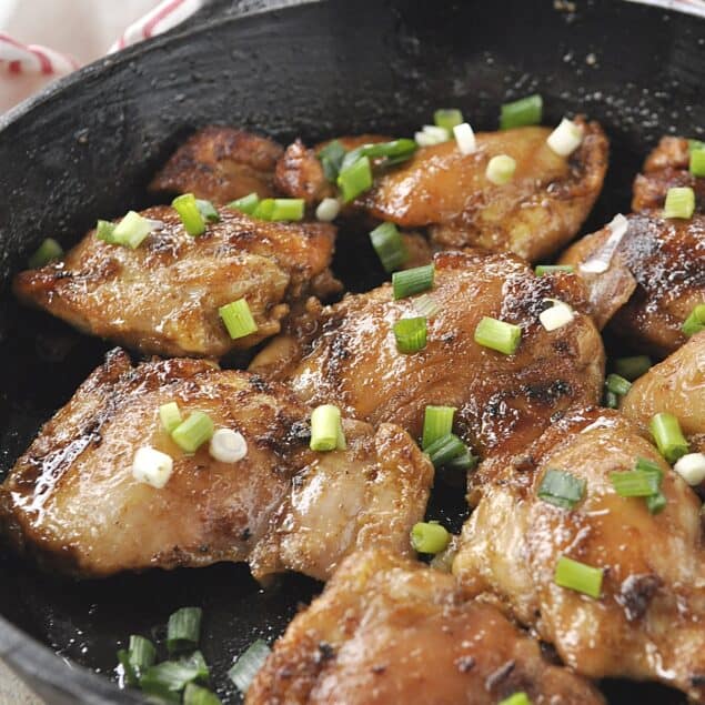 SPICY CHICKEN WITH GREEN ONIONS ON TOP IN A SKILLET