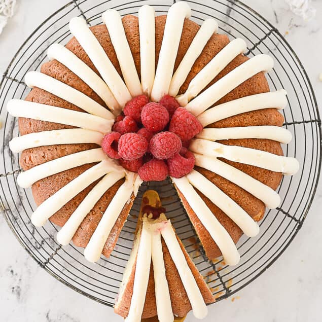 spatula removing a piece of white chocolate raspberry bundt cake