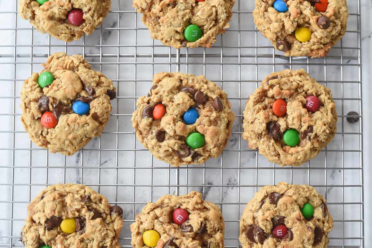 monster cookies with m & m's on top on a cooling rack
