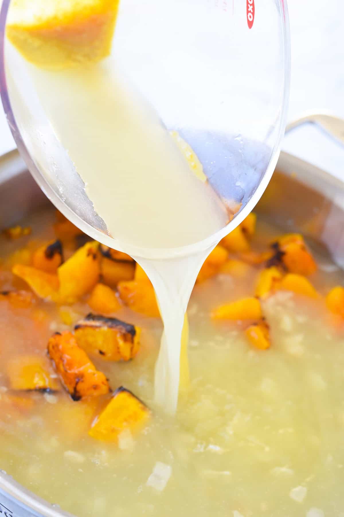 adding chicken broth to pan