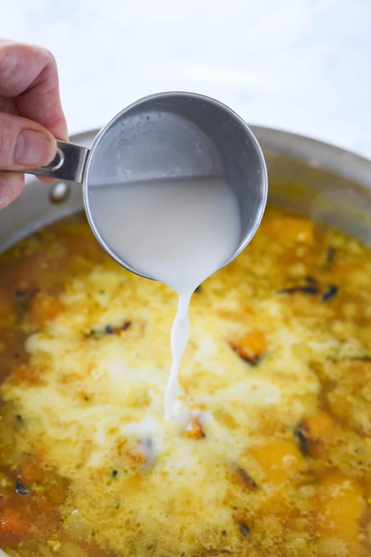 adding coconut milk to soup mixture