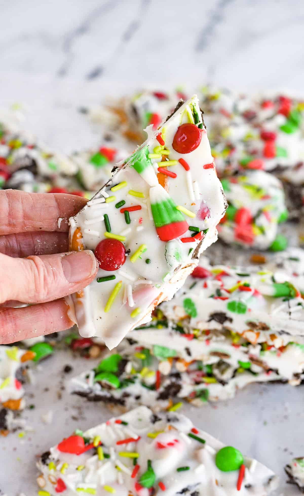 Christmas Cookie Bark hand holding a piece of christmas cookie bark