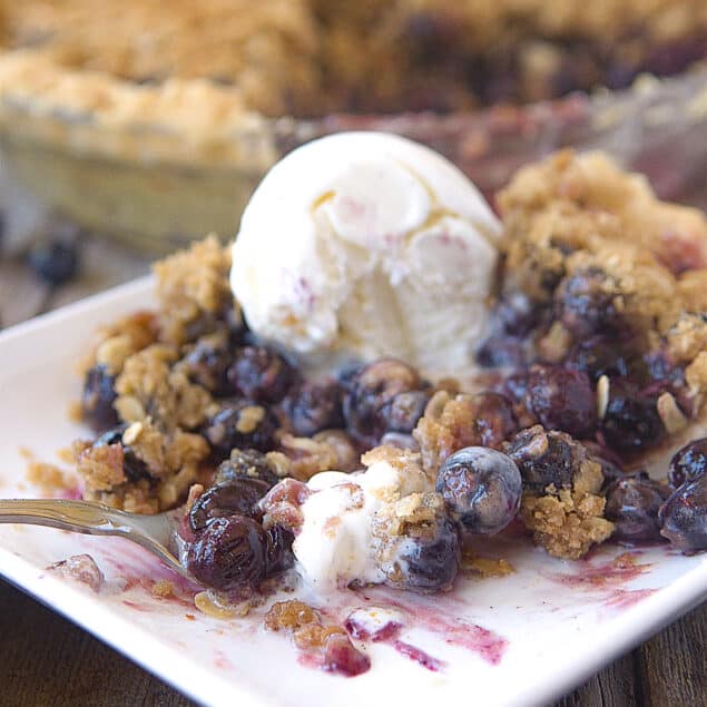 fork on a plate of blueberry pie with ice cream on top