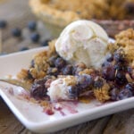 fork full of blueberry pie and ice cream on a plate