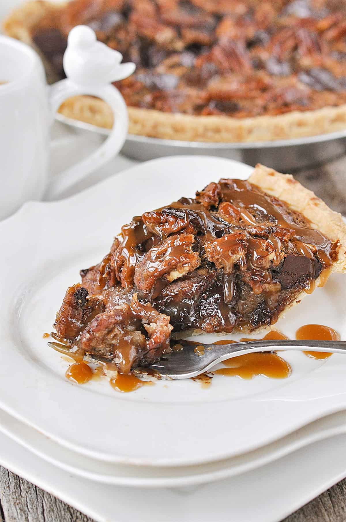 piece of chocolate pecan pie with caramel sauce on it and a fork