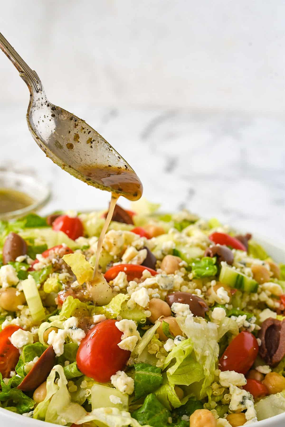 spooning dressing over greek salad