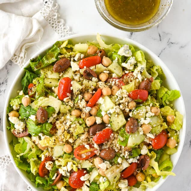 overhead shot of a bowl of greek salad with salad dressing on the side