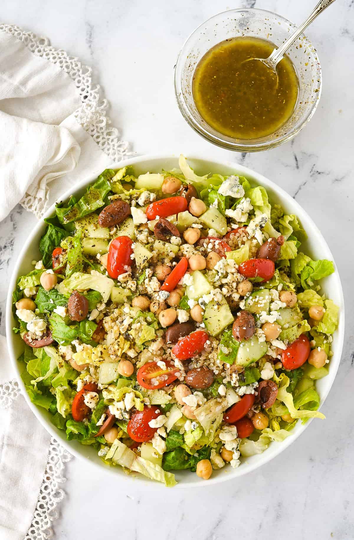 overhead shot of a bowl of greek salad with salad dressing on the side