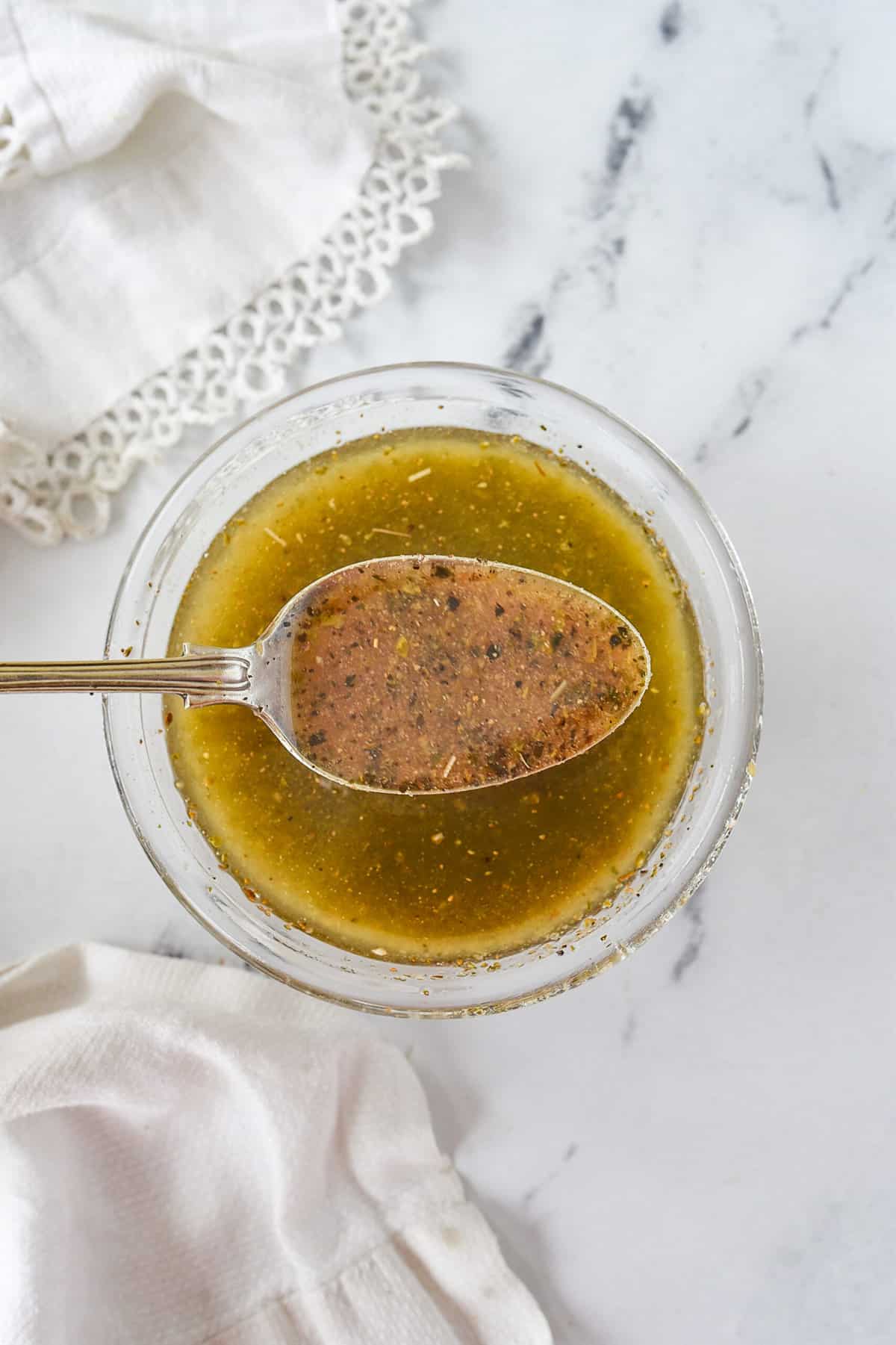 spoon of greek salad dressing over a bowl