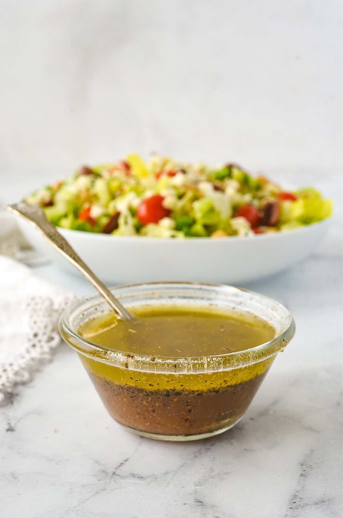 bowl of greek salad dressing in front of a salad