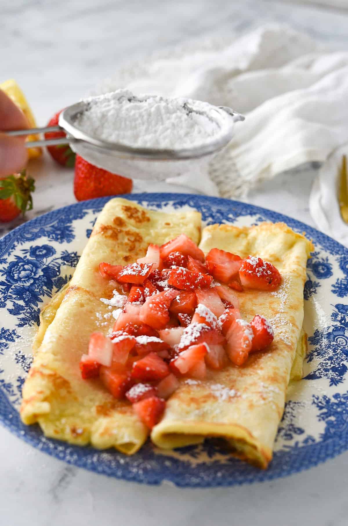 sprinkling powder sugar on swedish pancakes.