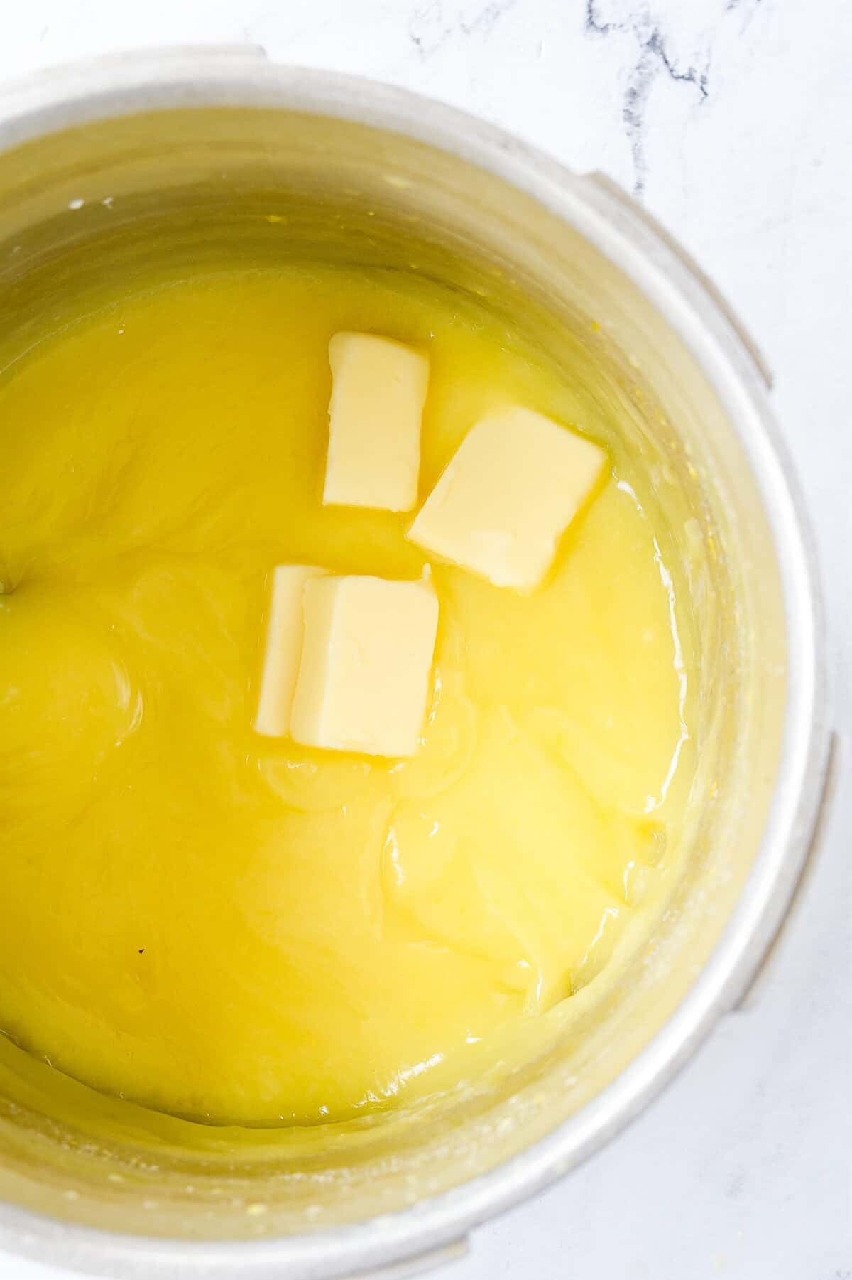 adding butter into lemon pie filling in a sauce pan