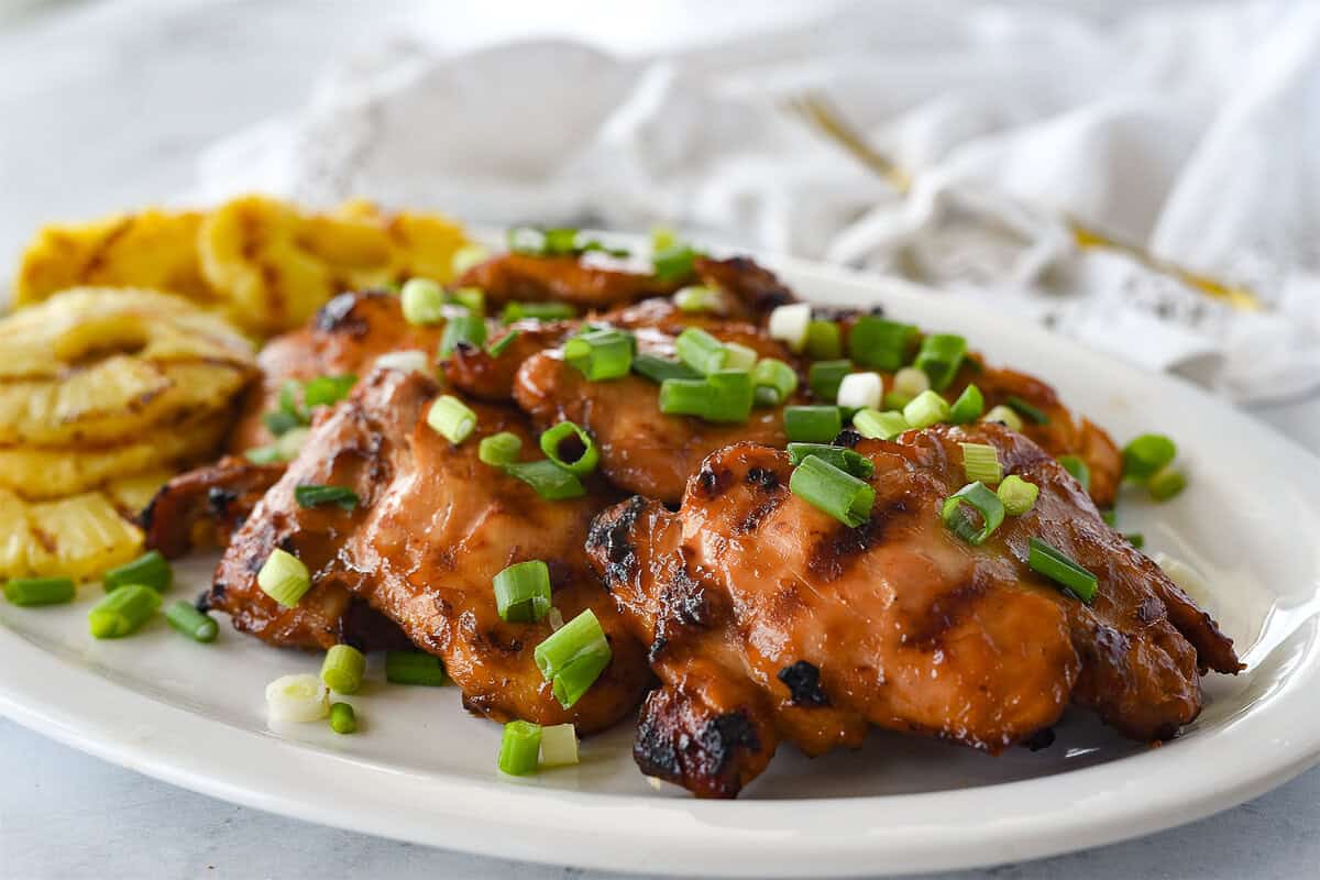 grilled huli huli chicken on a plate with green onion on top