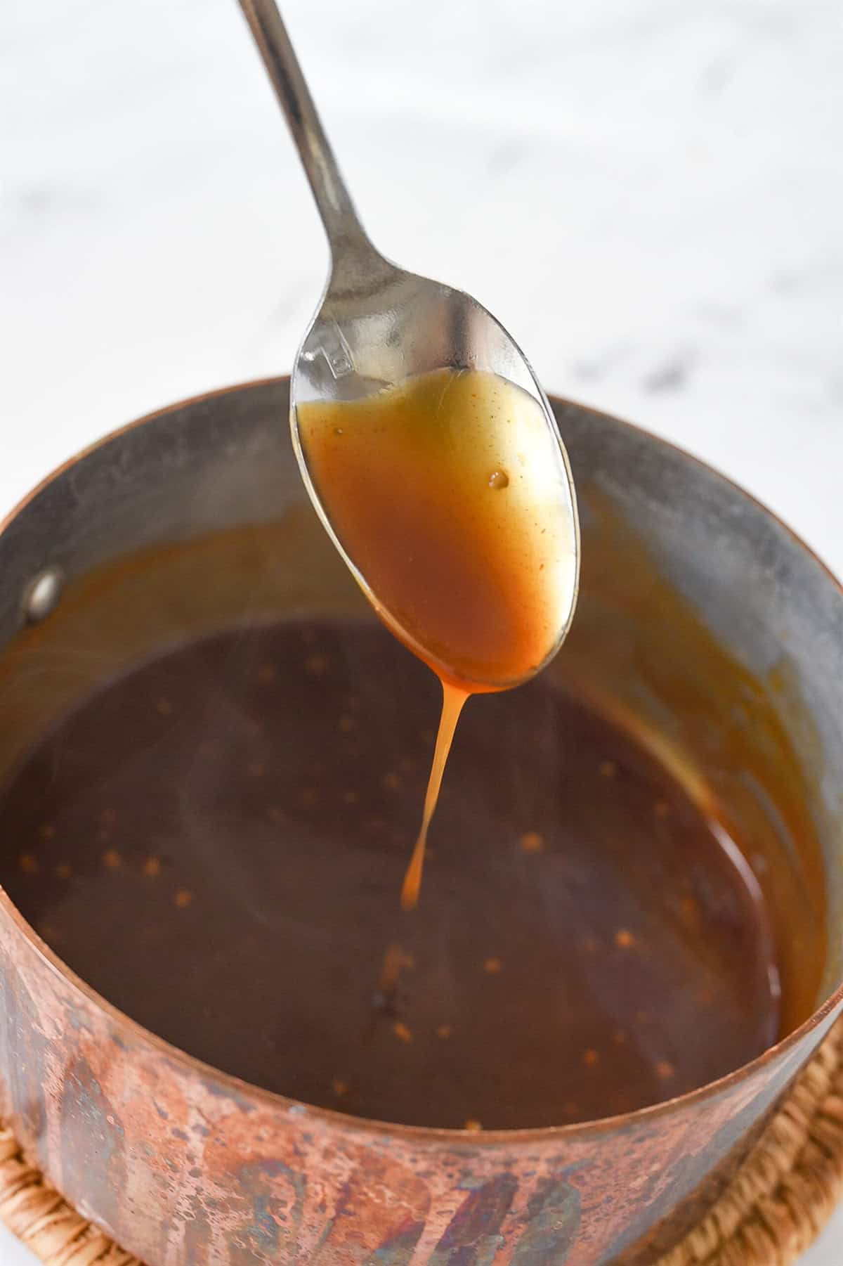 thickened sauce on a spoon in a pan