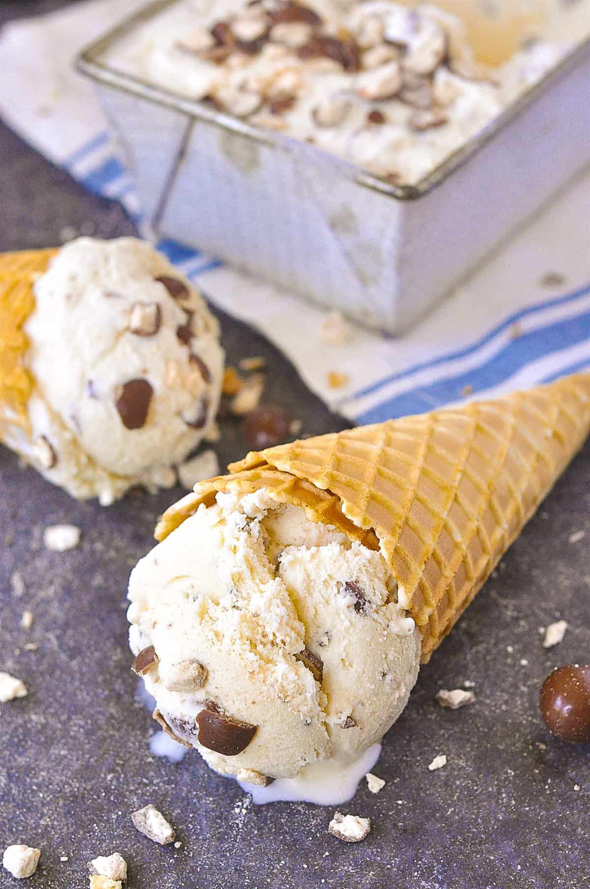 two ice cream cones lying on the counter with scoops of ice cream in them