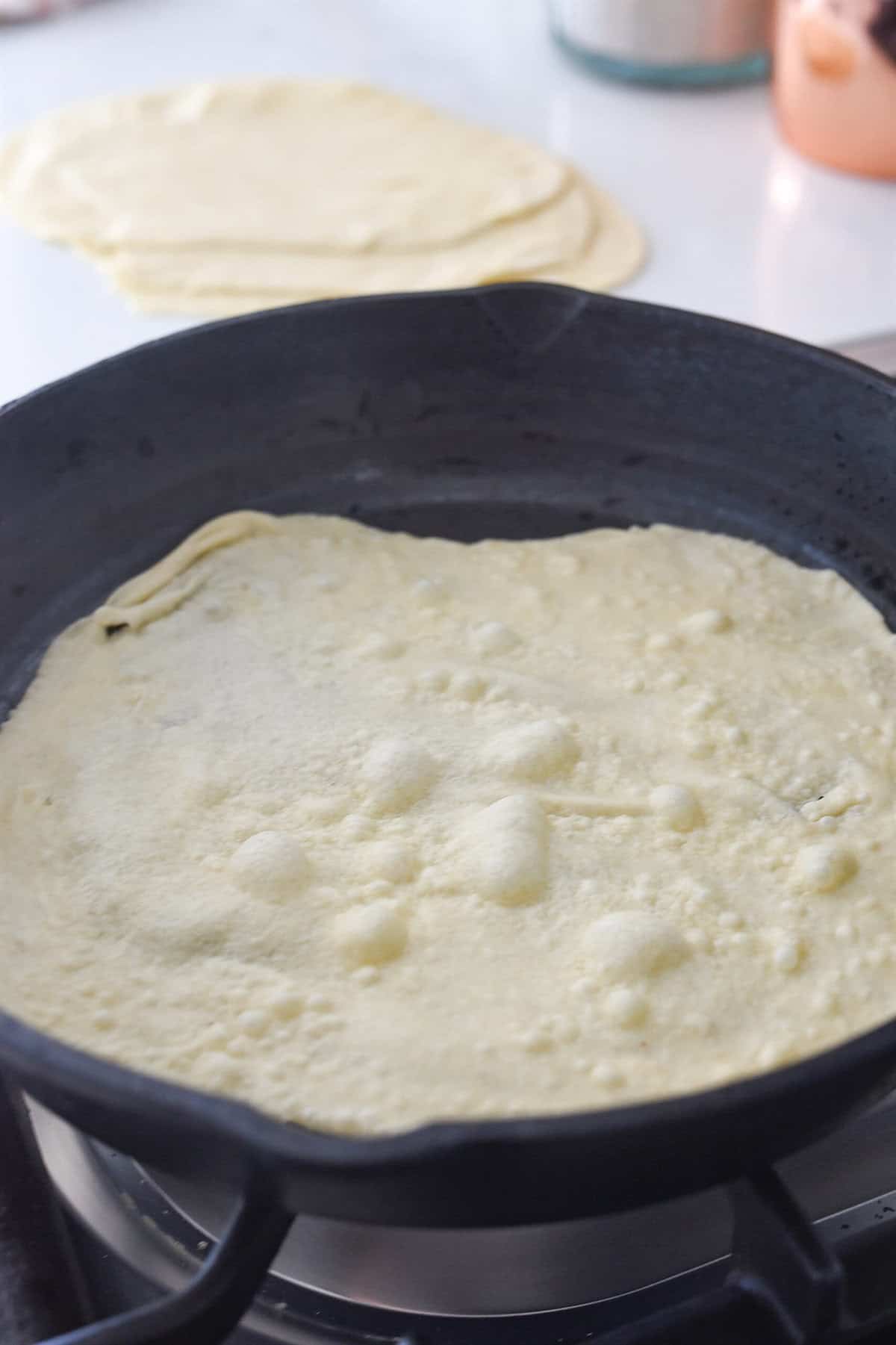 cooking a flour tortilla in a cast iron pan