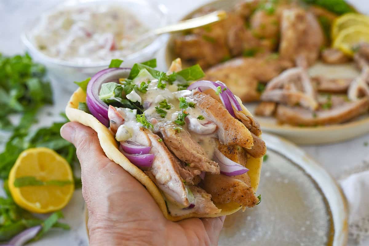 hand holding chicken shawarma in pita bread
