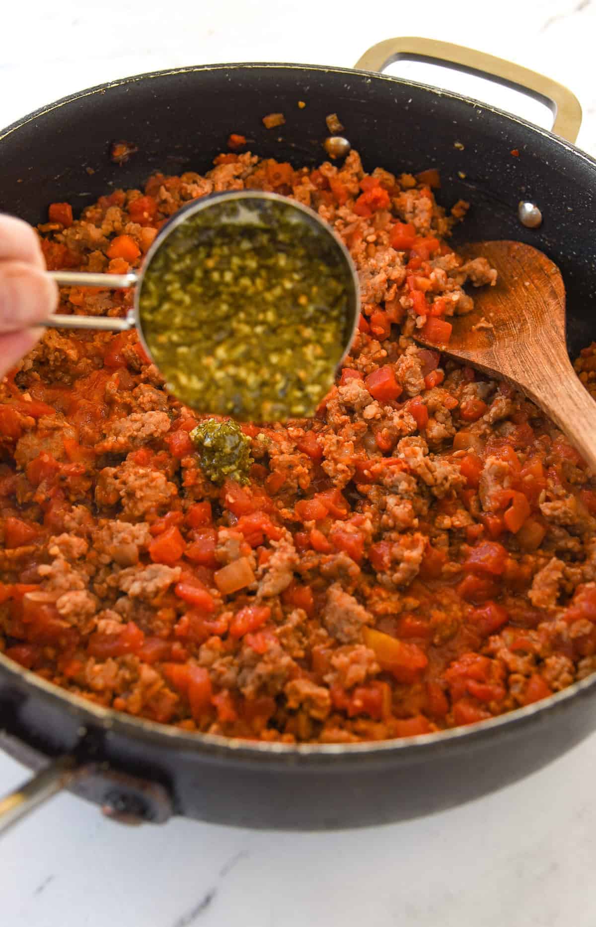 adding pesto to meat sauce