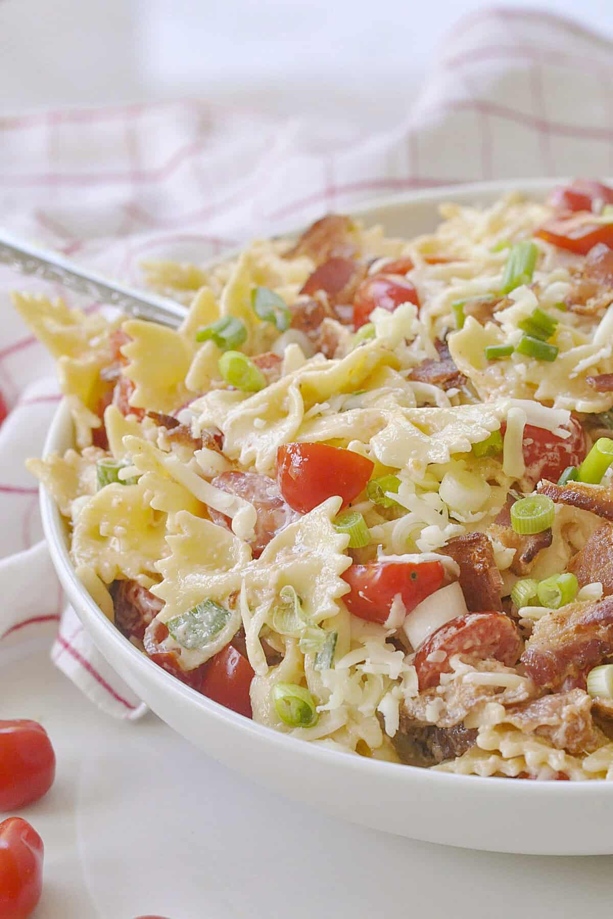 blt pasta salad recipe blt pasta salad in a white bowl with a spoon in it