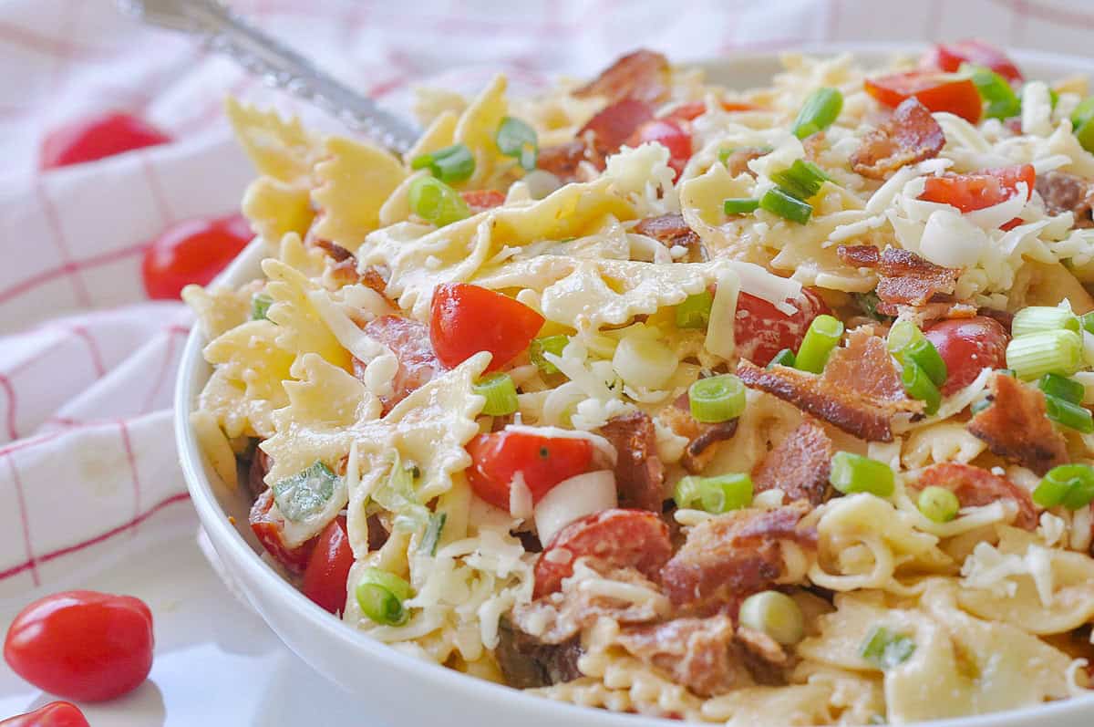 blt pasta salad in a white bowl with tomatoes on top
