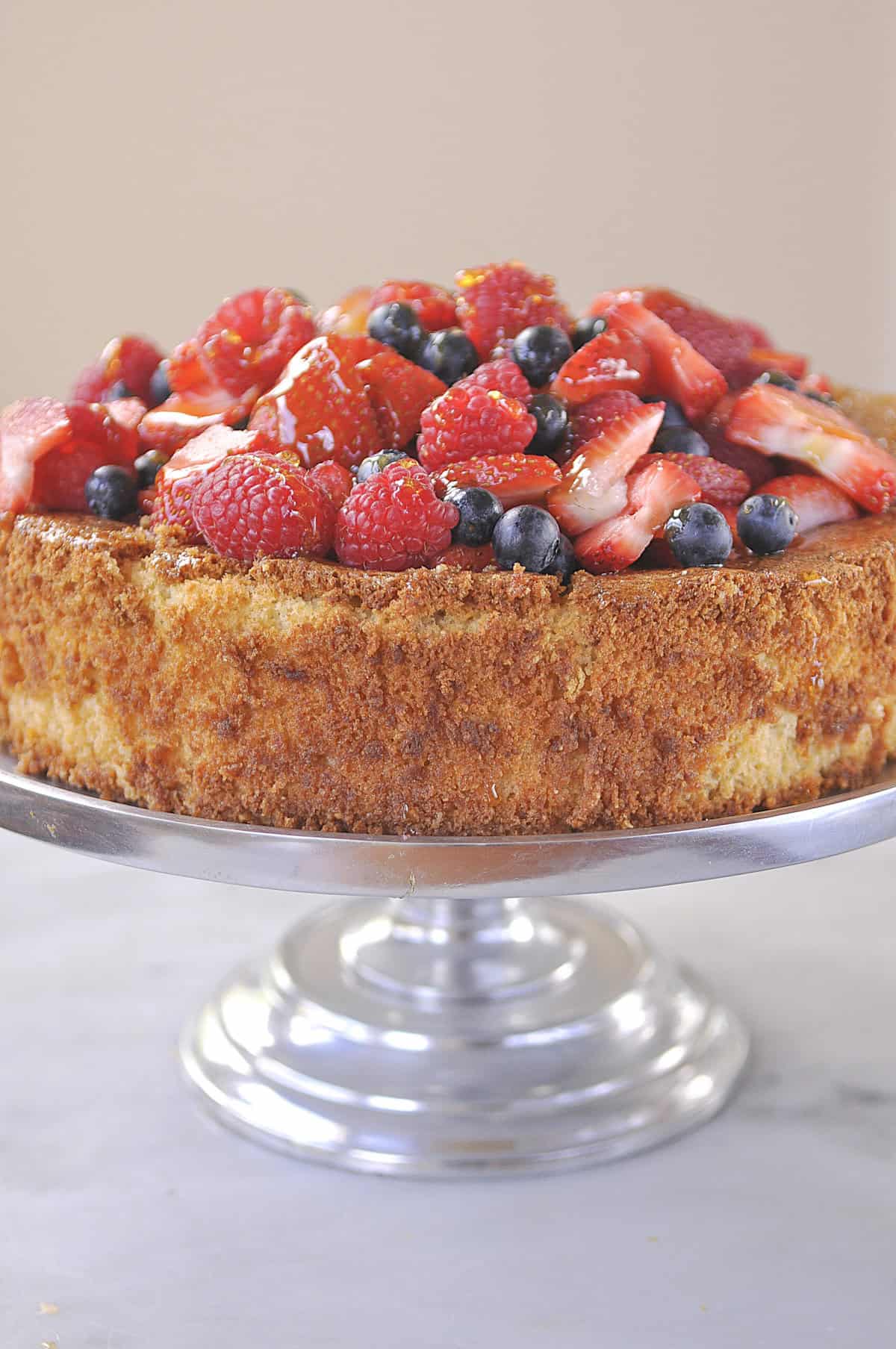 almond cake with berrie s on a cake stand.