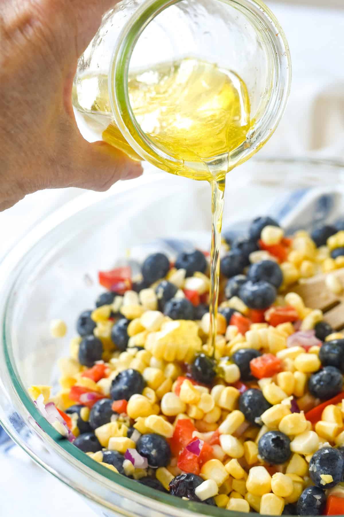 pouring dressing over blueberry corn salad