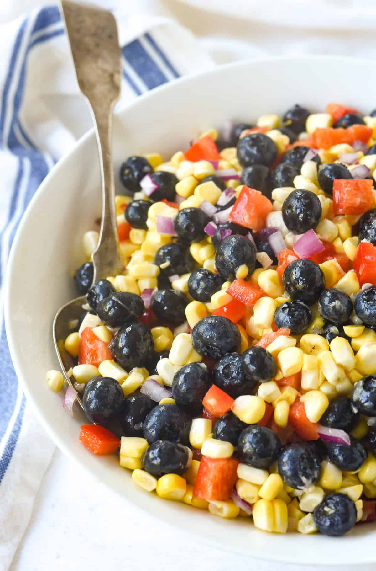 spoon in a bowl of blueberry corn salad