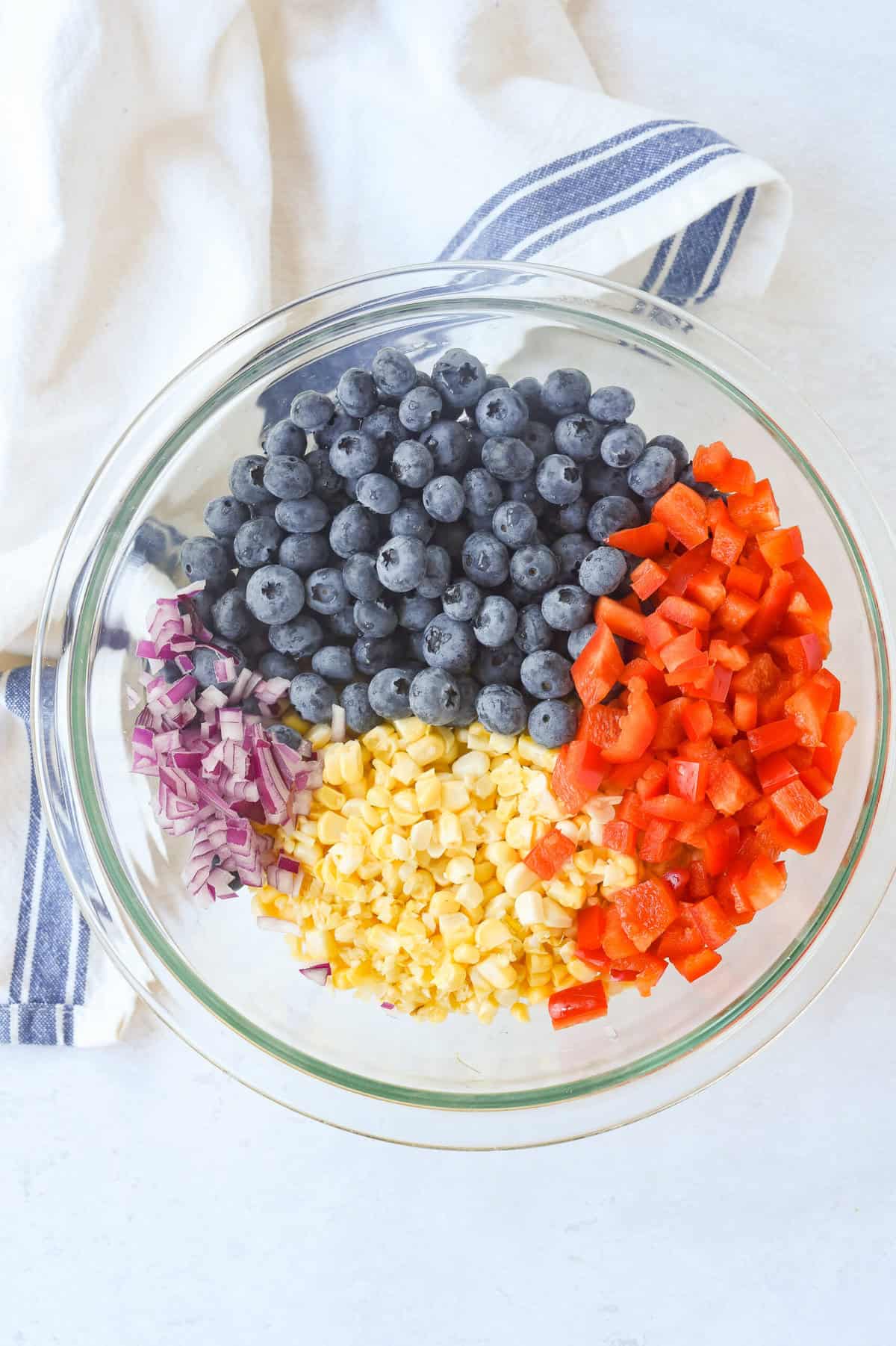 bowl with chopped corn, blueberry, onion and red pepper in it