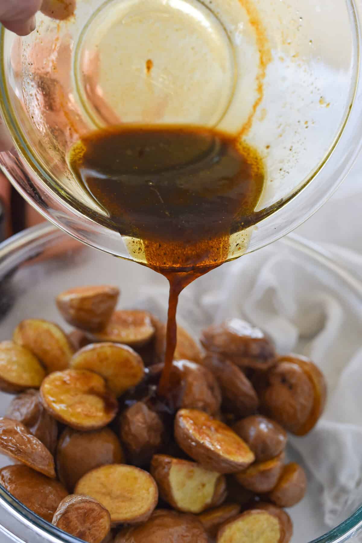 pouring balsamic vinegar mixture over cooked potatoes