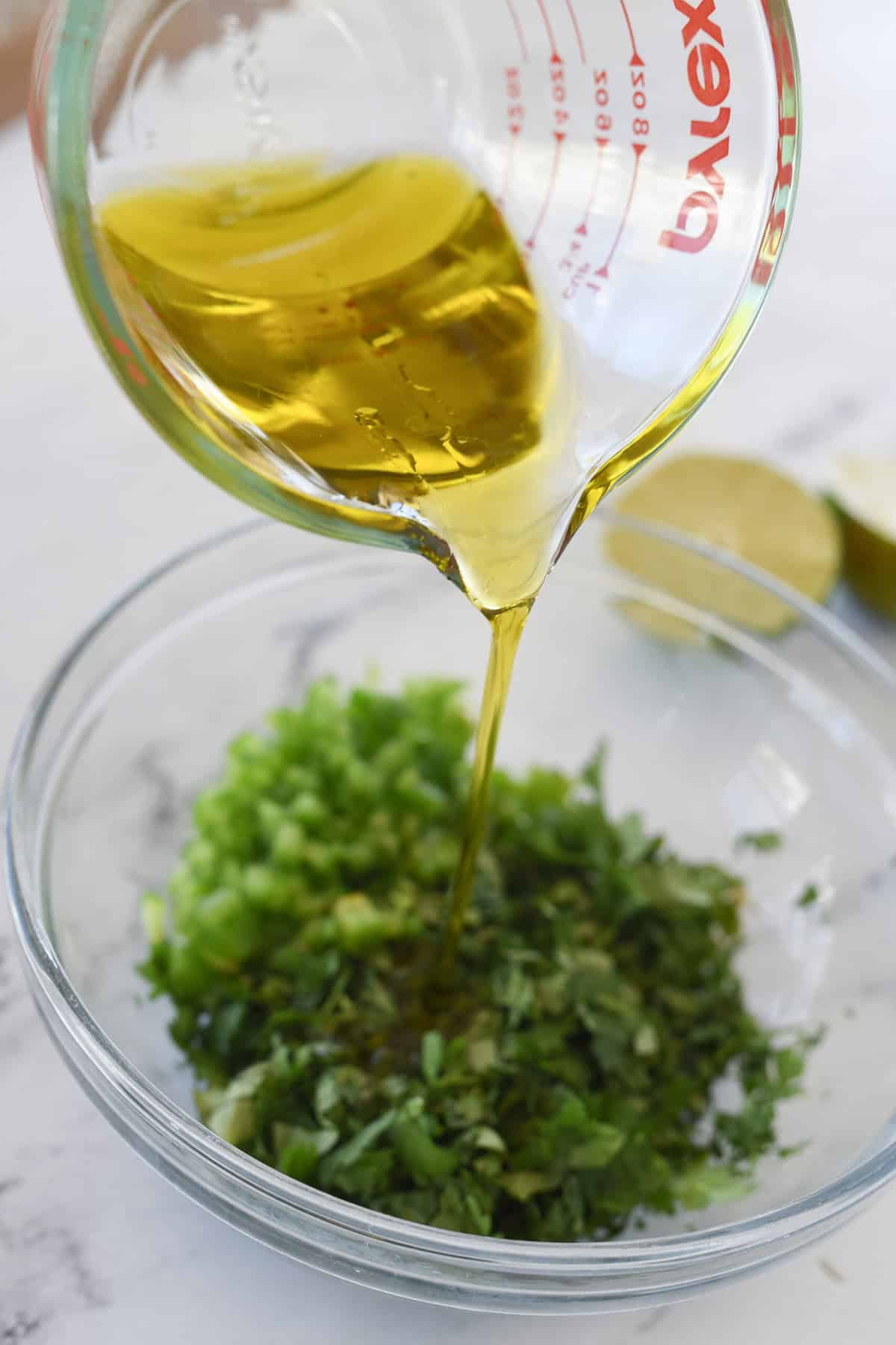 pouring olive oil into chimichurri sauce
