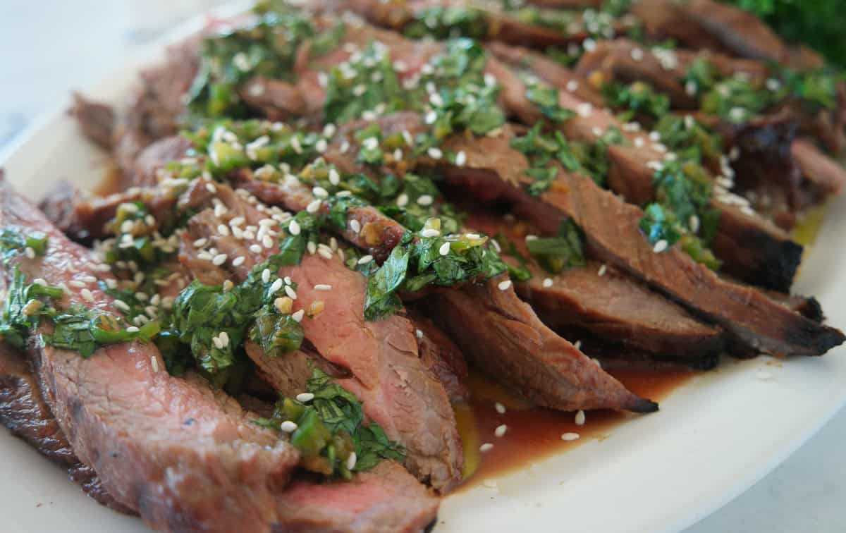 closeup shot of flank steak with chimchurri sauce on it
