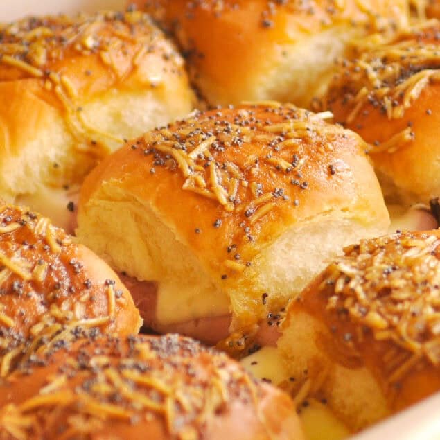 baked ham and cheese sliders in a white baking dish