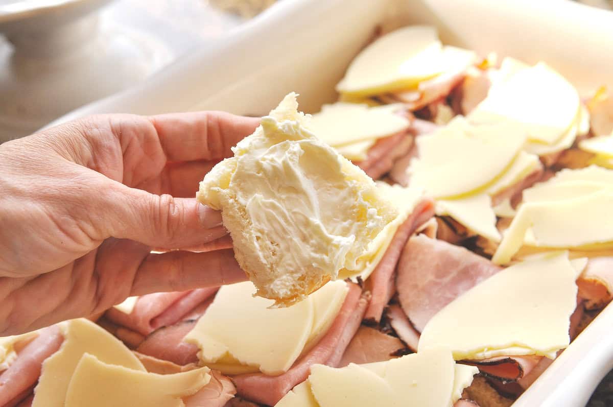 spreading cream cheese on a slider roll