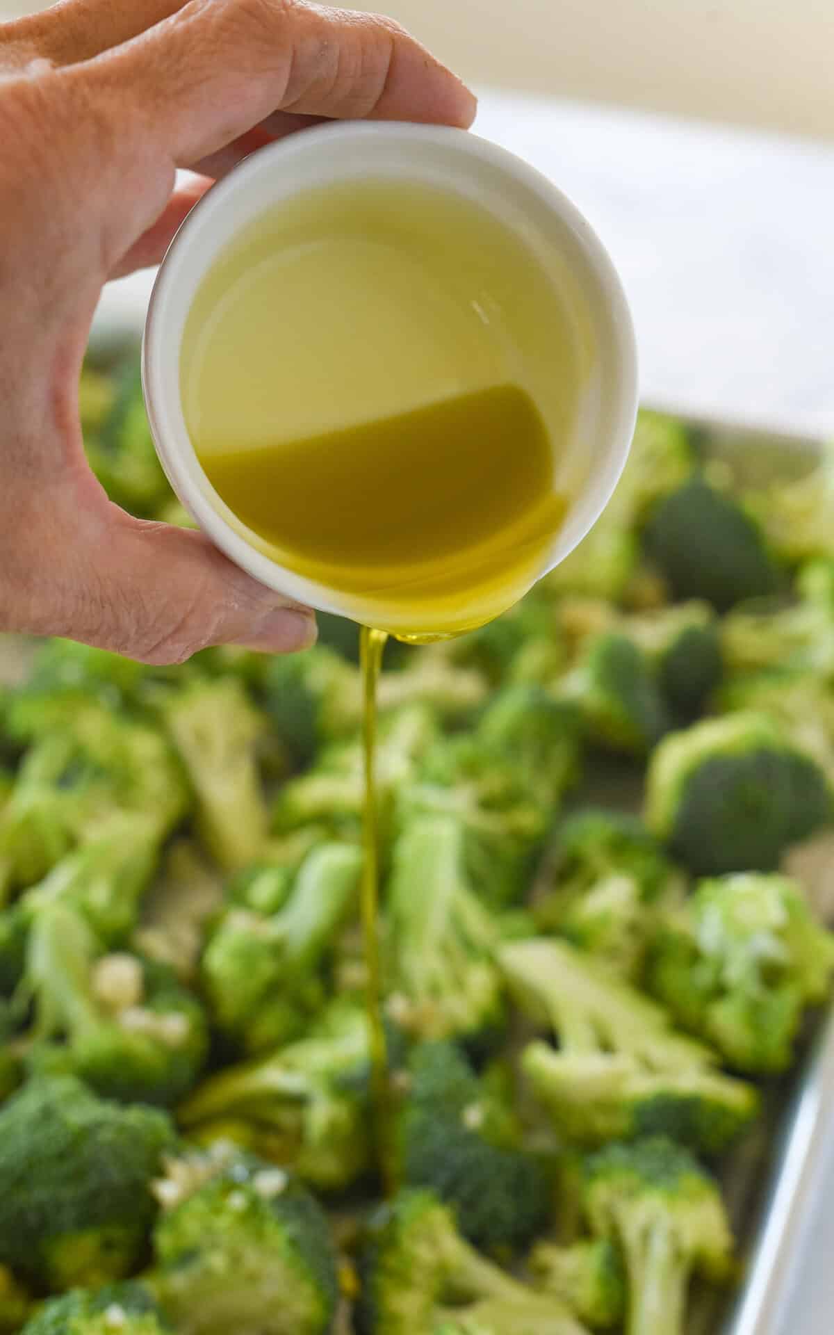 pouring olive oil on broccol