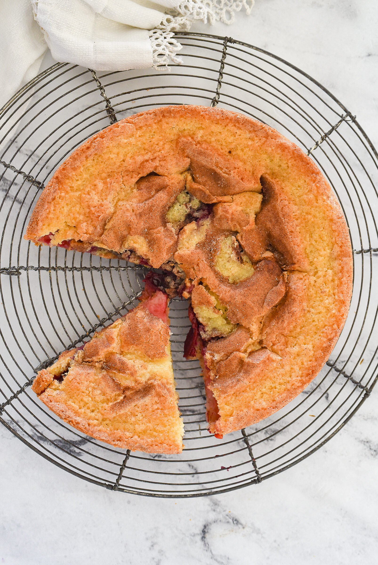 overhead shot of plum cake with a piece cut out of it