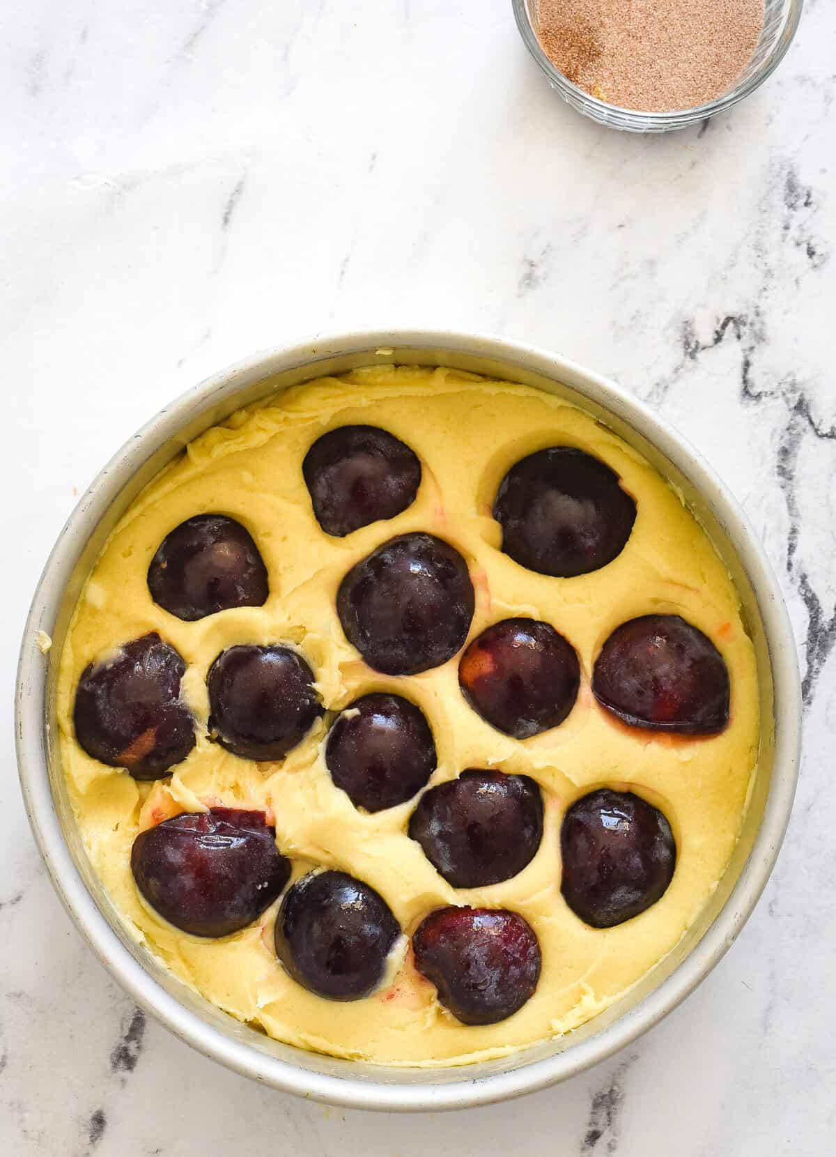 cake batter and plums in a cake pan