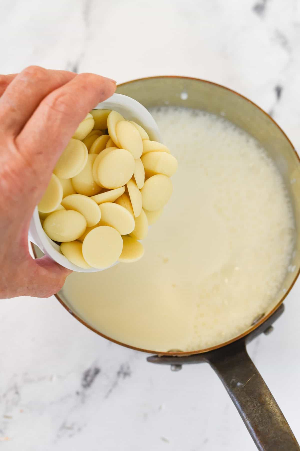 adding white chocolate to milk in a pan
